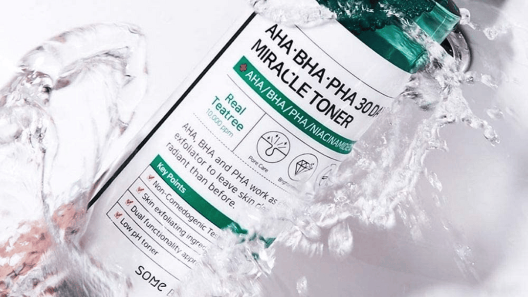 En flaska av SOME BY MI AHA-BHA-PHA 30 Days Miracle Toner omgiven av sprutande vatten, vilket framhäver produktens uppfriskande och rengörande effekt.