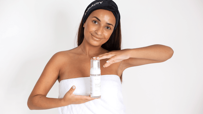 En kvinna i en vit handduk och ett svart hårband med texten 