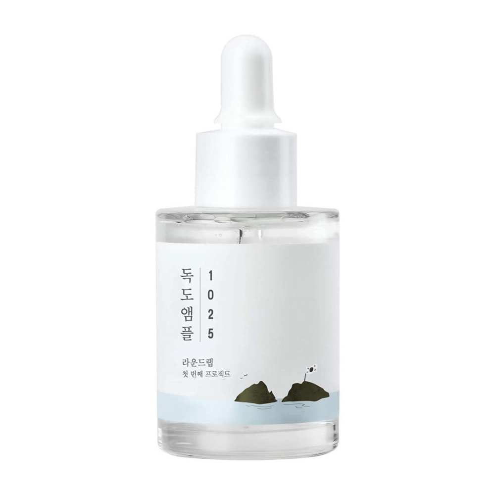 Una botella transparente con 1025 Dokdo Ampoule suero facial, decorada con un tema marino minimalista, sobre un fondo blanco.
