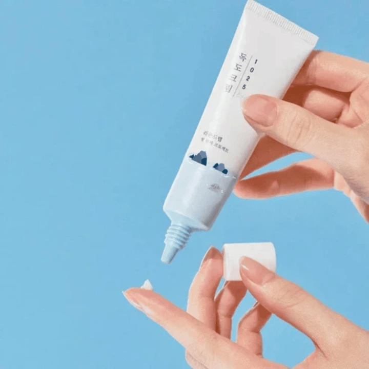 Round Lab 1025 Dokdo Eye Cream tubo con crema ligera que se aplica en la yema del dedo para el cuidado suave de la piel sensible alrededor de los ojos