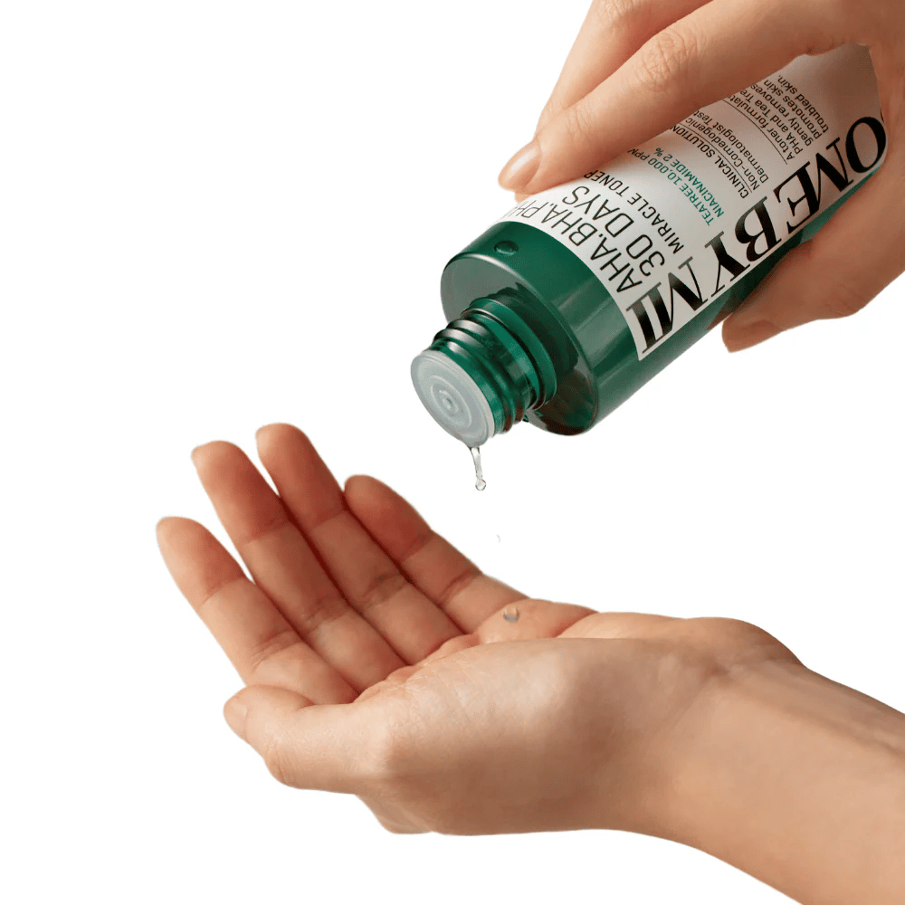 Una mano sostiene una botella verde con el texto "AHA, BHA, PHA 30 Days Miracle Toner" y exprime un líquido claro en la palma de la otra mano, listo para su uso.