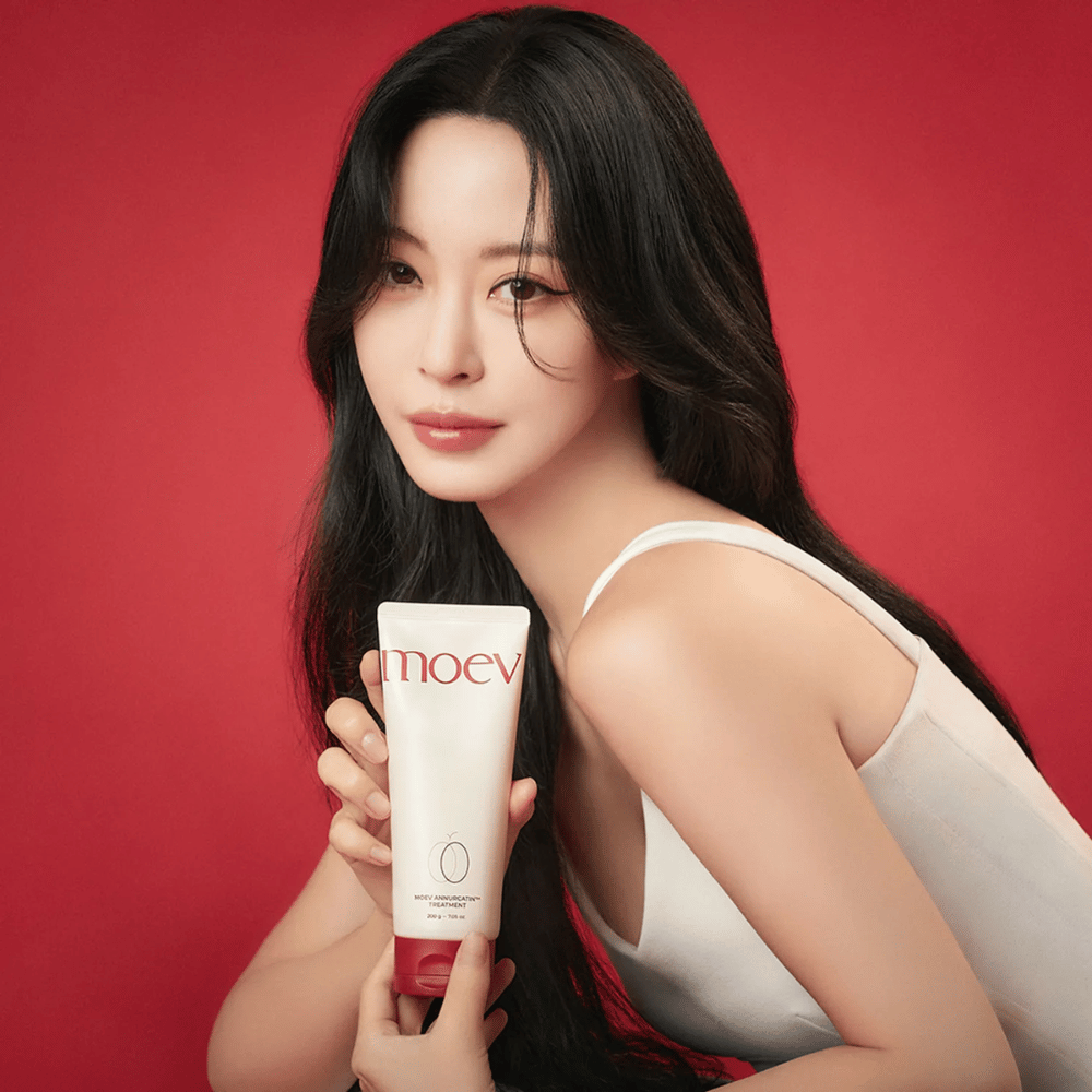 Mujer con cabello largo y brillante sostiene MOEV Annurcatin Treatment – cuidado capilar coreano que proporciona nutrición, fuerza y brillo con ingredientes naturales.