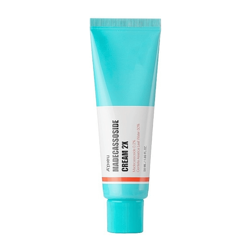 Un tubo con A'PIEU Madecassoside Cream 2X, con un color turquesa claro en la parte superior que se desvanece a blanco hacia la base. El tubo tiene texto claro que indica la marca y el nombre del producto, así como el ingrediente activo Madecassoside 2%. Un color de acento naranja forma una línea alrededor del tubo. El producto parece ser una crema para la piel enfocada en el cuidado y reparación de la piel. El fondo es neutral para mantener el enfoque en el producto.