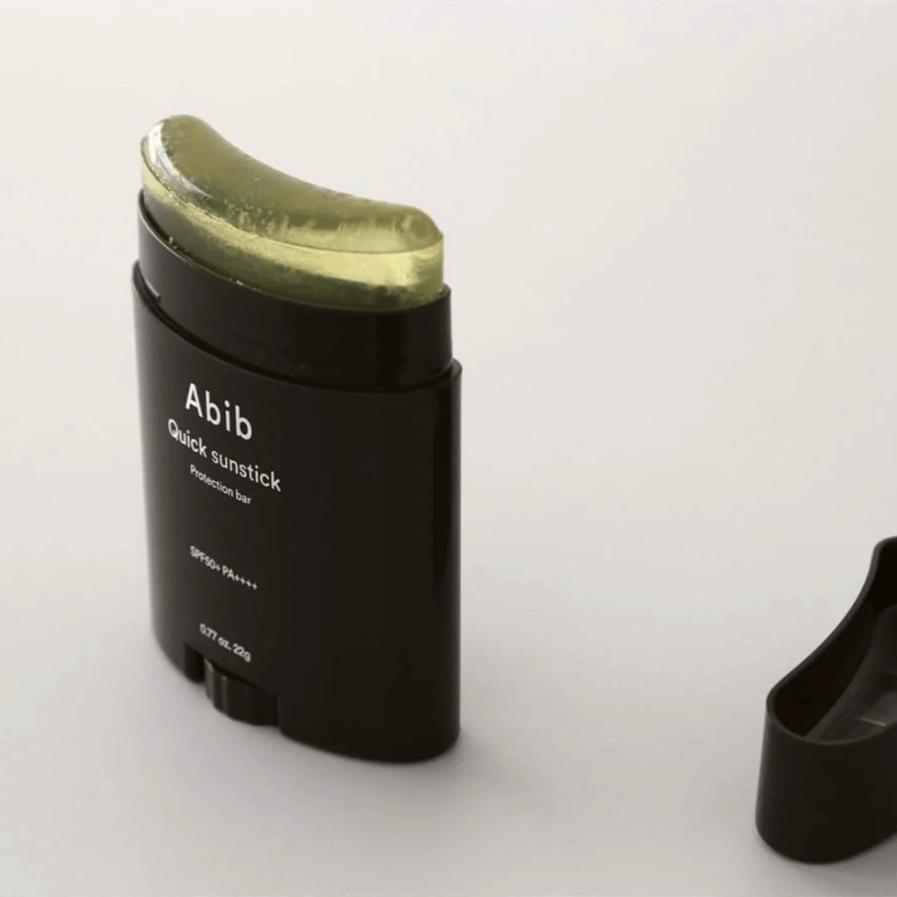 Un tubo negro con tapa verde, que contiene Quick Sunstick Protection Bar SPF50+ PA++++ 22g de Abib para protección solar.