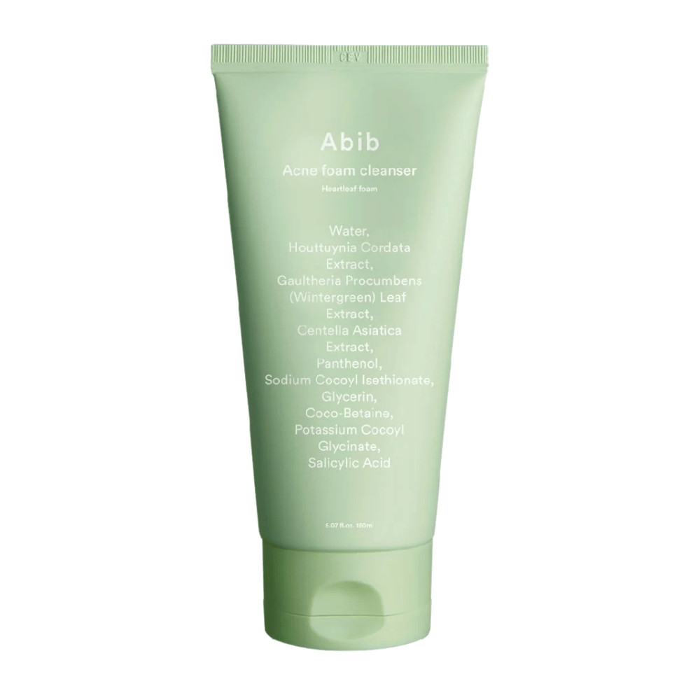 Tubo verde con Abib Acne Foam Cleanser Heartleaf Foam, mostrando ingredientes como Houttuynia Cordata, Centella Asiatica y Ácido Salicílico impresos en el frente. El producto está de pie contra un fondo blanco.