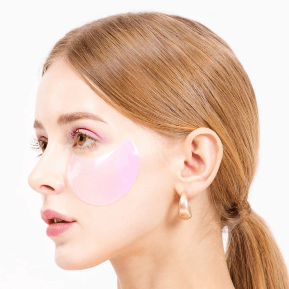 Modelo lleva un parche de hidrogel rosa para ojos debajo del ojo, hidratante y rejuvenecedor de la piel.