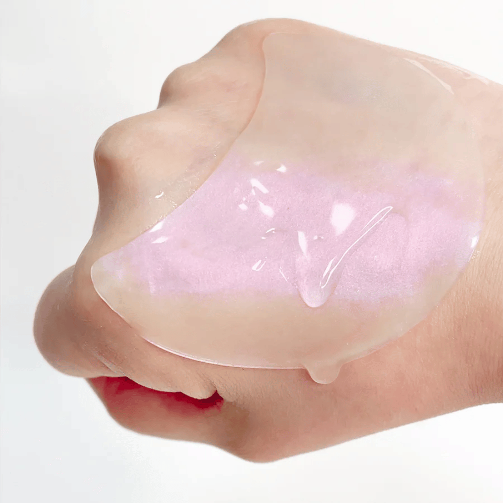 Parche de hidrogel rosa para ojos con retinol se muestra en una mano, fórmula hidratante y que da brillo.