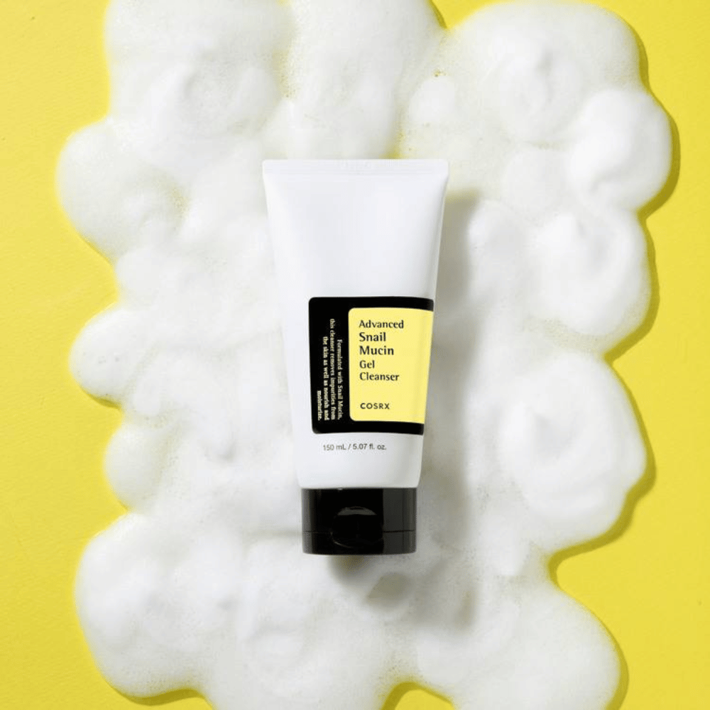 COSRX Advanced Snail Mucin Gel Cleanser 150 ml rodeado de abundante espuma sobre fondo amarillo – limpieza facial coreana suave con snail mucin para hidratación y brillo.