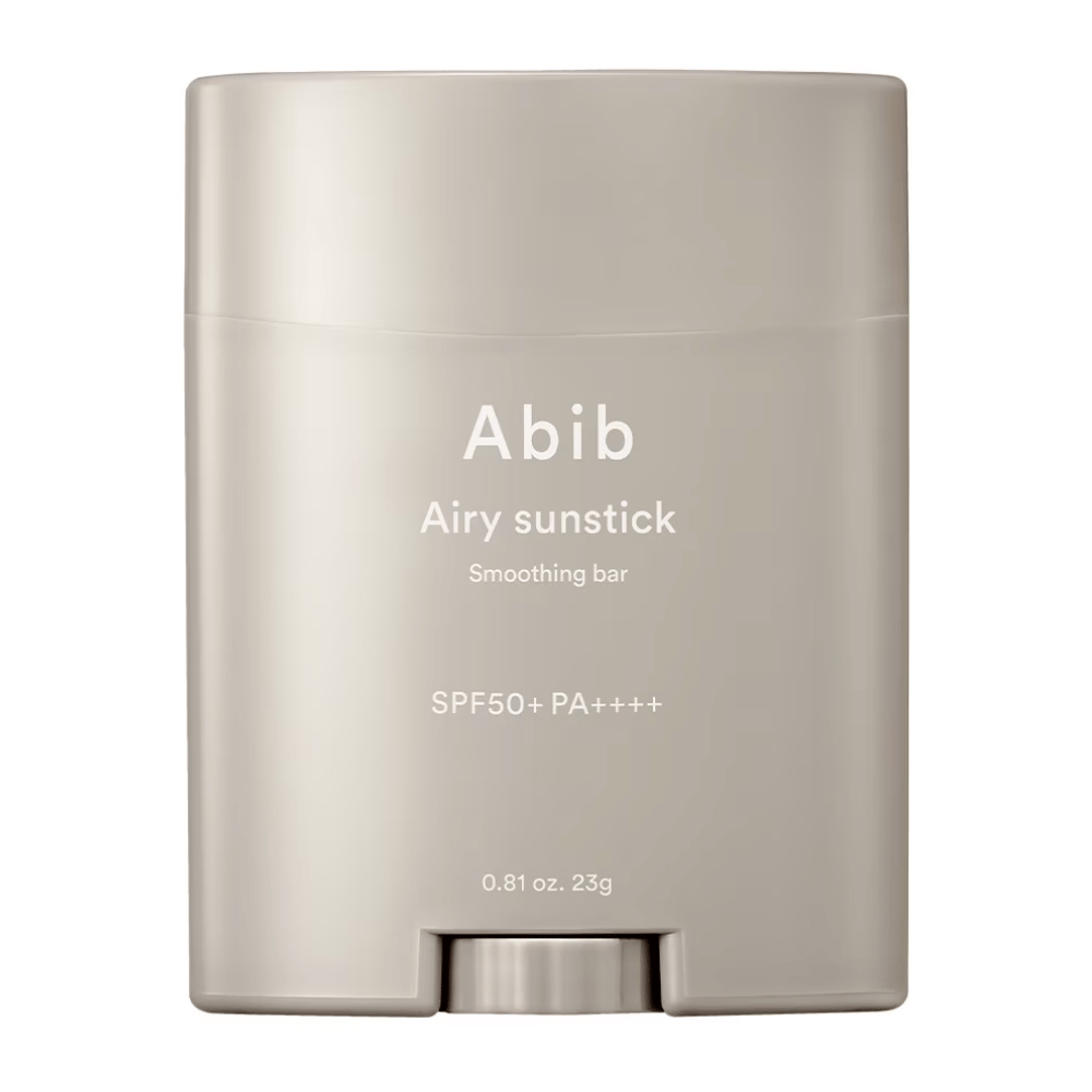 La imagen muestra un protector solar en barra beige de Abib con el texto "Airy Sunstick Smoothing Bar" y factor de protección solar SPF50+ PA++++, perfecto para la protección diaria contra los rayos UV.