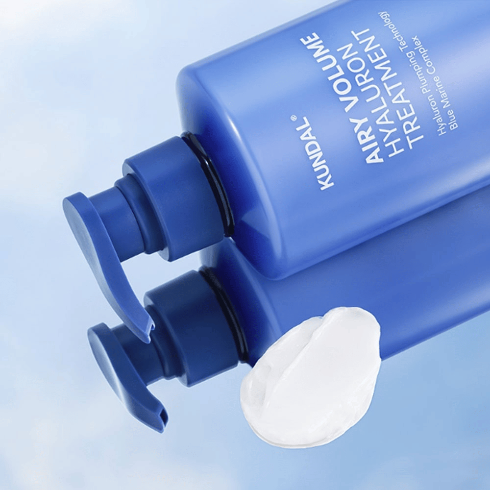 KUNDAL Airy Volume Hyaluron Treatment en botella de bomba azul acostada, con producto de crema blanca visible al lado.