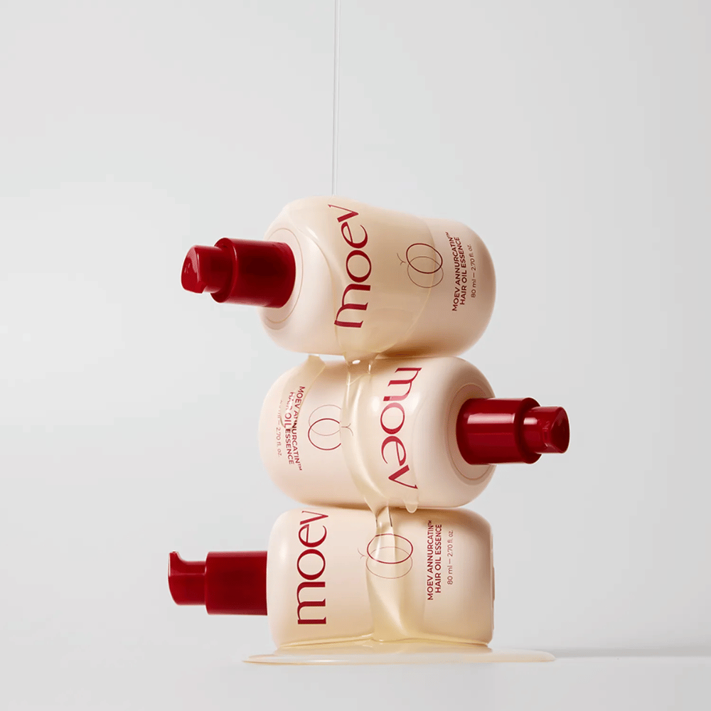 Tres botellas MOEV Annurcatin Hair Oil Essence apiladas – aceite capilar nutritivo con manzana Annurca y biotina que fortalece, protege y da brillo y elasticidad al cabello.