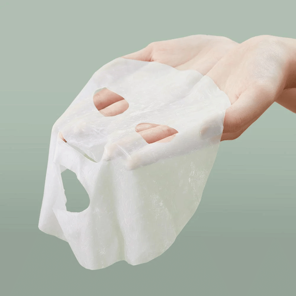 La mano de una persona que sostiene Anua Heartleaf 77% Soothing Sheet Mask.