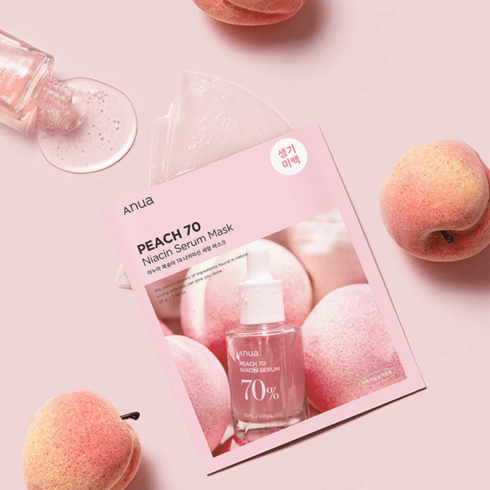 Una imagen de Anua PEACH 70 Niacin Serum Mask, rodeada de duraznos y una botella de suero. La imagen tiene un fondo rosa suave, lo que complementa el empaque rosa y resalta el producto y los ingredientes.