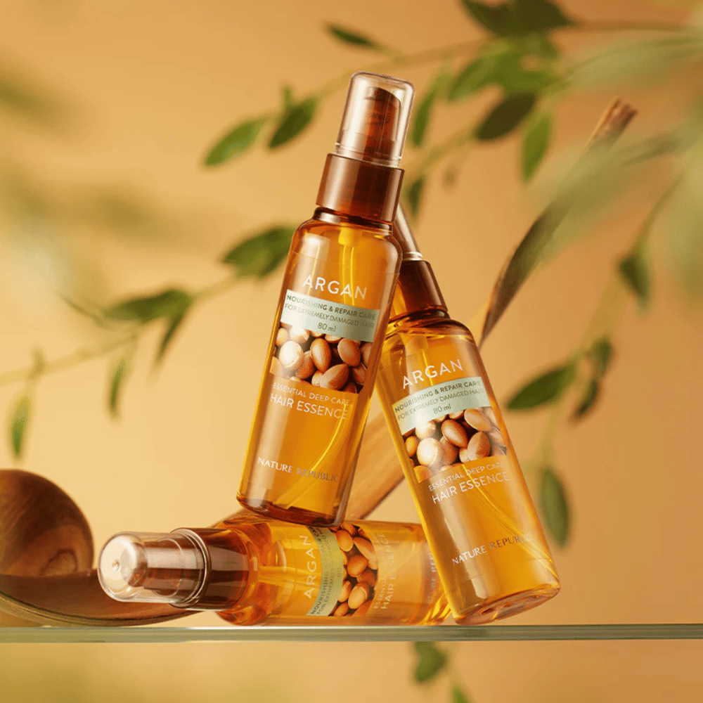 Tres botellas de Nature Republic Argan Essential Moisture Hair Oil con aceite de argán – proporciona nutrición, brillo y repara el cabello dañado.