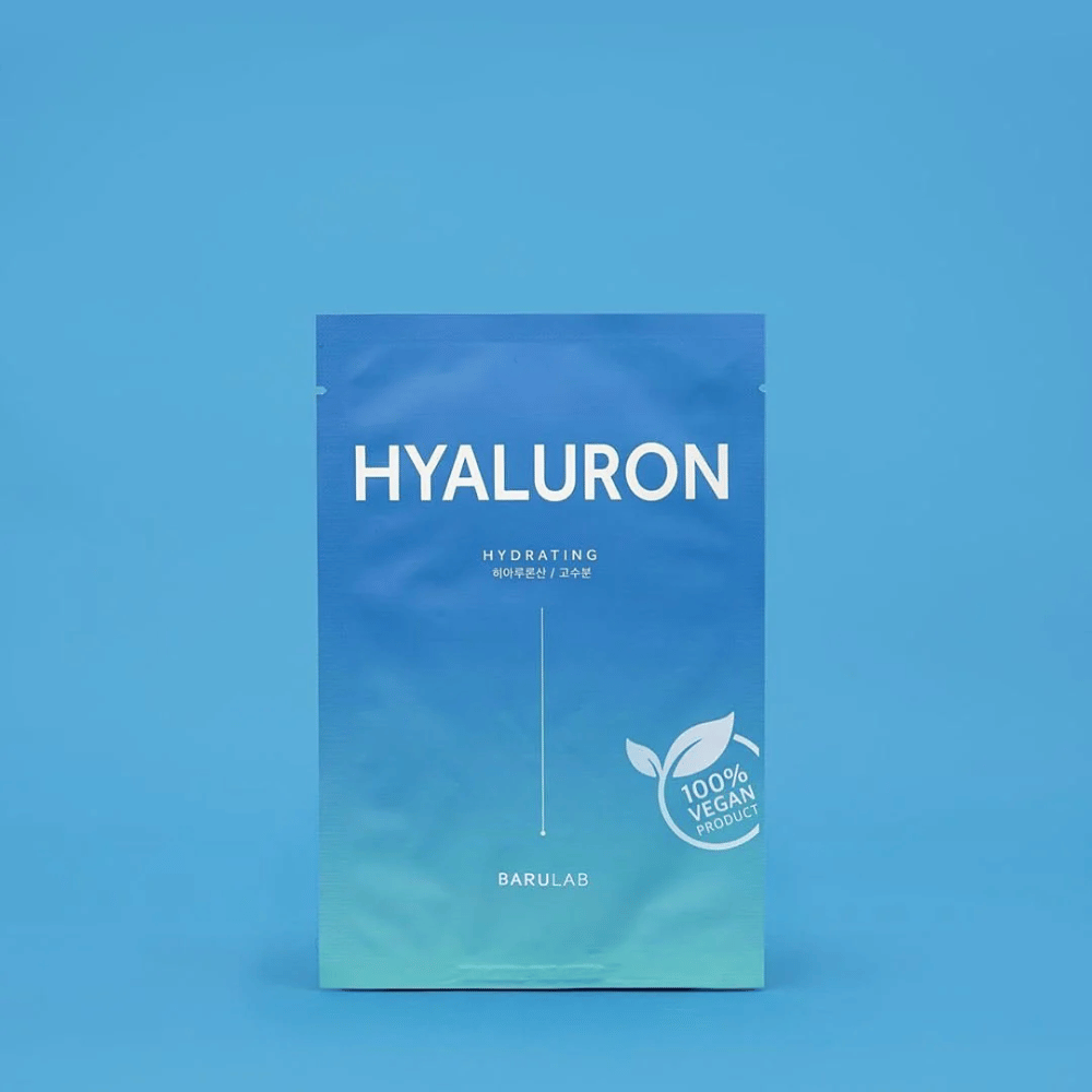 Un paquete de BARULAB máscara "HYALURON Hydrating", etiquetado como "100% Producto Vegano", frente a un fondo azul uniforme. El paquete tiene un degradado de color de azul oscuro a azul claro.