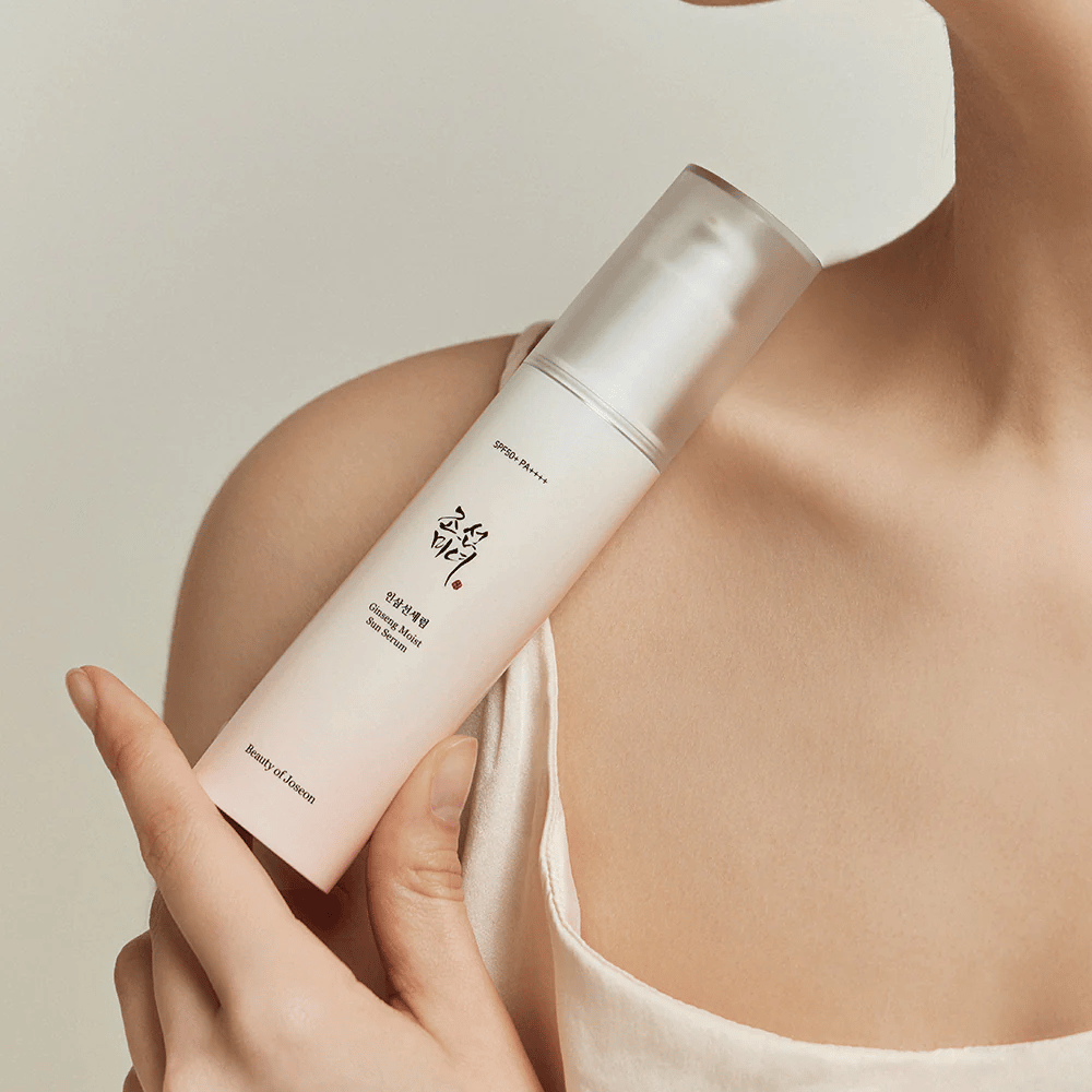 Una mujer sosteniendo una botella de Beauty of Joseon's Ginseng Moist Sun Serum SPF 50+ PA++++, que ofrece protección 50+ PA++++ y beneficios para el cuidado de la piel.