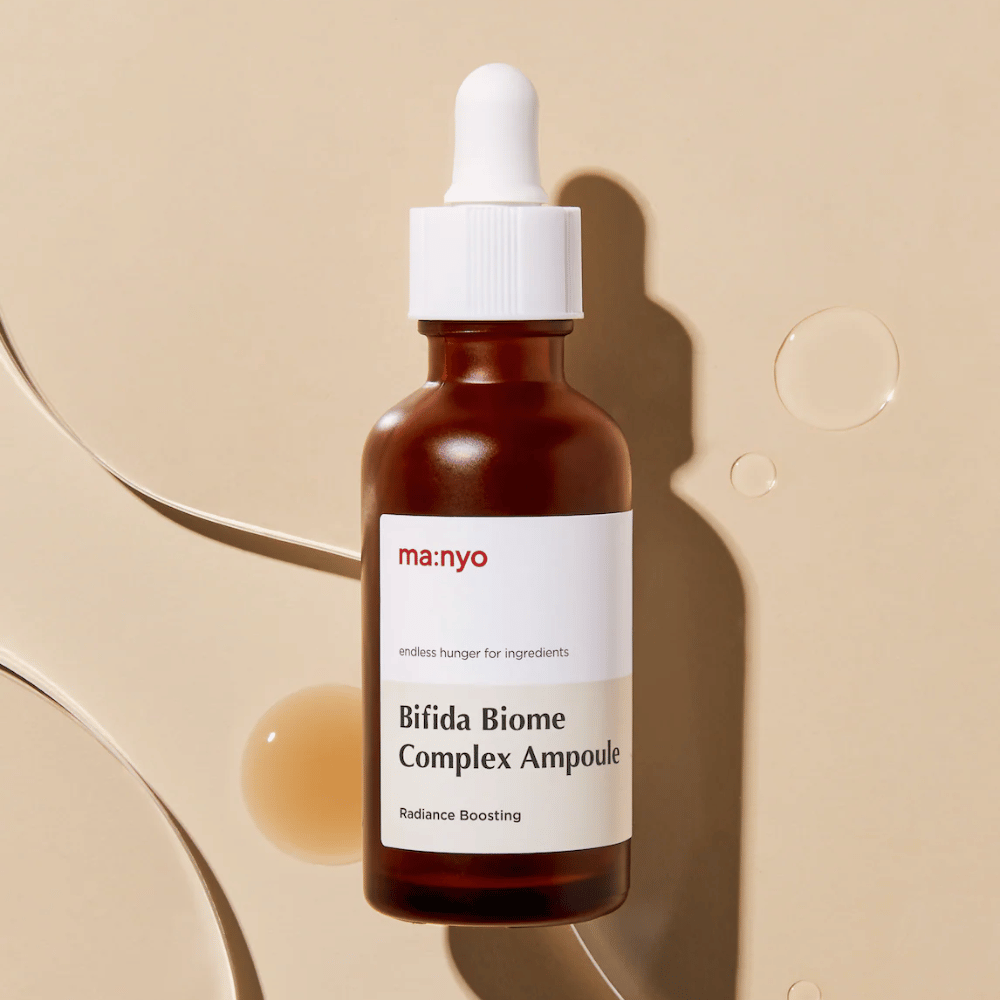 Imagen de producto elegante de ma:nyo Bifida Biome Complex Ampoule con enfoque en el diseño de la botella y gotas de sérum en el fondo.
