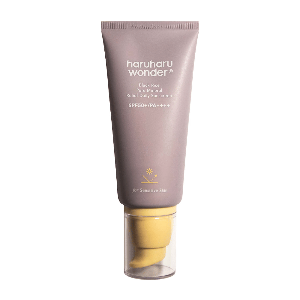 Un tubo lila con Haruharu Wonder Black Rice Pure Mineral Relief Daily Sunscreen SPF 50+ PA++++. El tubo tiene una tapa transparente y texto que describe el alto nivel de protección del protector solar, especialmente adaptado para piel sensible.
