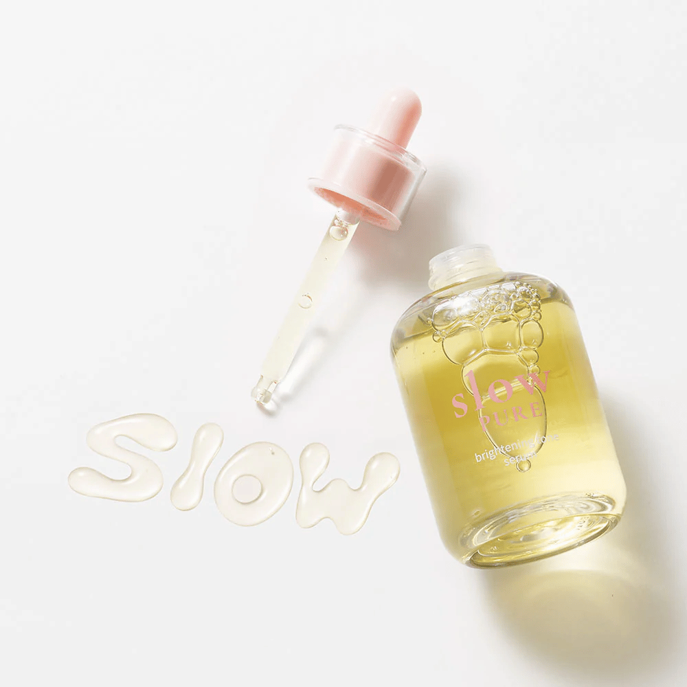 Slow Pure Brightening Tone Serum con pipeta abierta, texto escrito en suero sobre la superficie: "Slow".