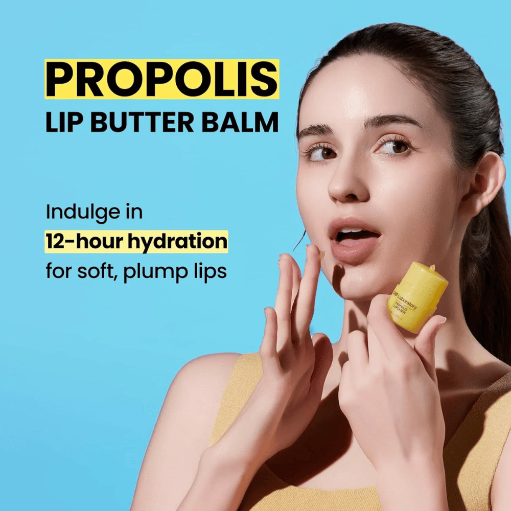 Una mujer aplica CNP Laboratory Propolis Lip Butter Balm, resaltado contra un fondo azul. El producto promete 12 horas de hidratación para labios suaves y llenos, lo cual se muestra con un tubo amarillo que sostiene en la mano.
