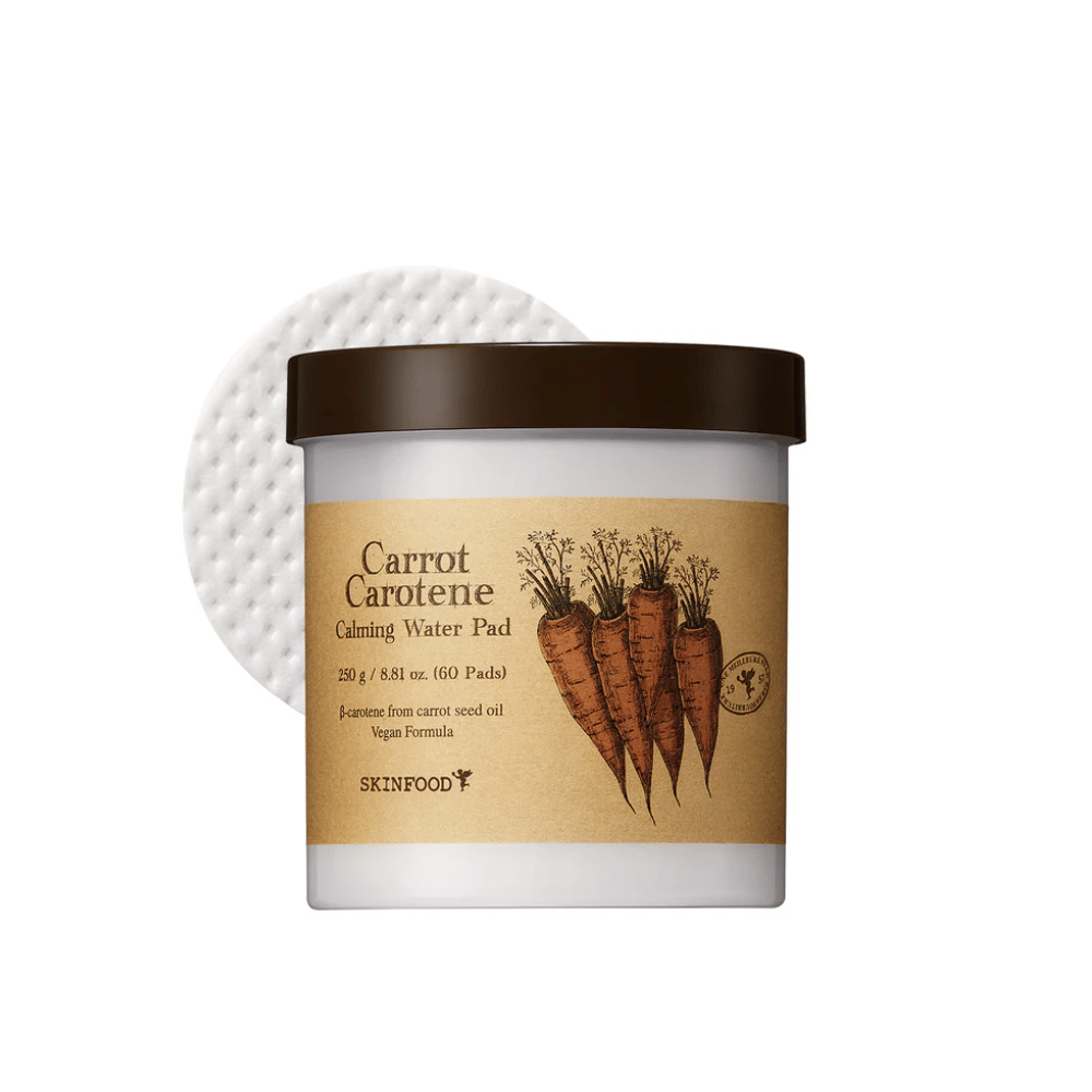 Un frasco "Carrot Carotene Calming Water Pad" de SKINFOOD. El frasco contiene 60 almohadillas y está etiquetado con una imagen de zanahorias. El producto, que está basado en aceite de semilla de zanahoria, es apto para veganos y está diseñado para calmar la piel.