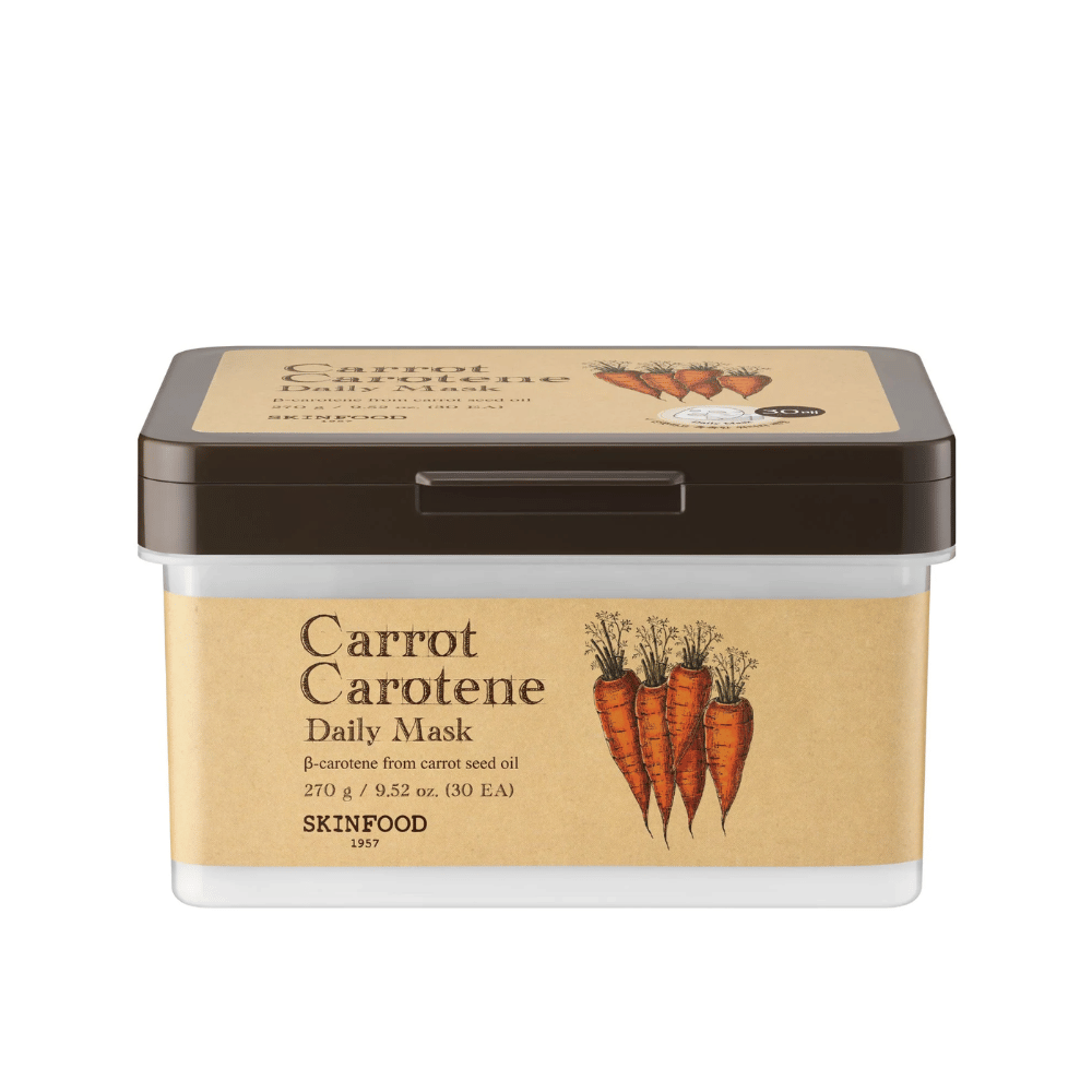 Un paquete "Carrot Carotene Daily Mask" de SKINFOOD, que contiene 30 mascarillas faciales. El producto está enriquecido con β-caroteno de aceite de semilla de zanahoria y está diseñado para uso diario. El paquete es robusto con una etiqueta de inspiración vintage que resalta las zanahorias como ingrediente principal.