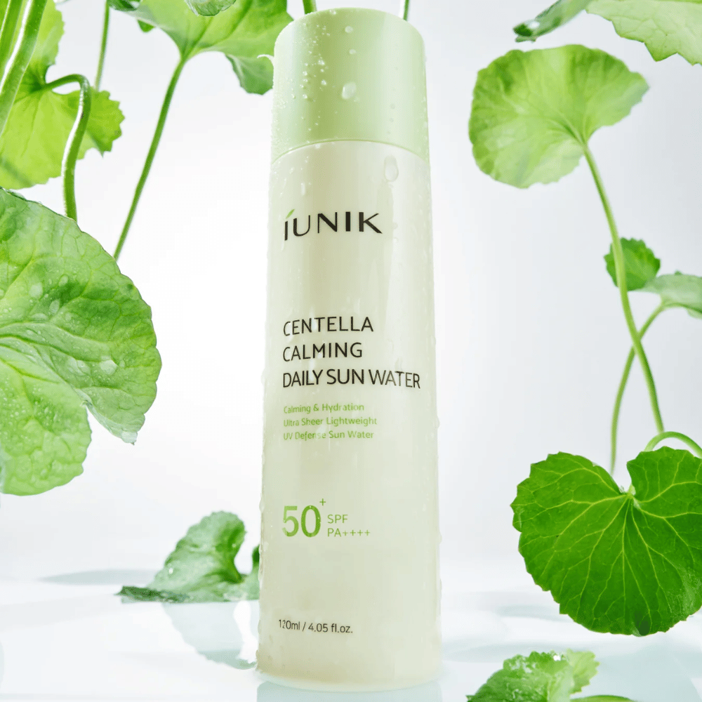 2. iUNIK Centella Calming Daily Sun Water SPF50+ PA++++ – protector solar hidratante con centella asiática rodeado de hojas verdes y gotas de agua