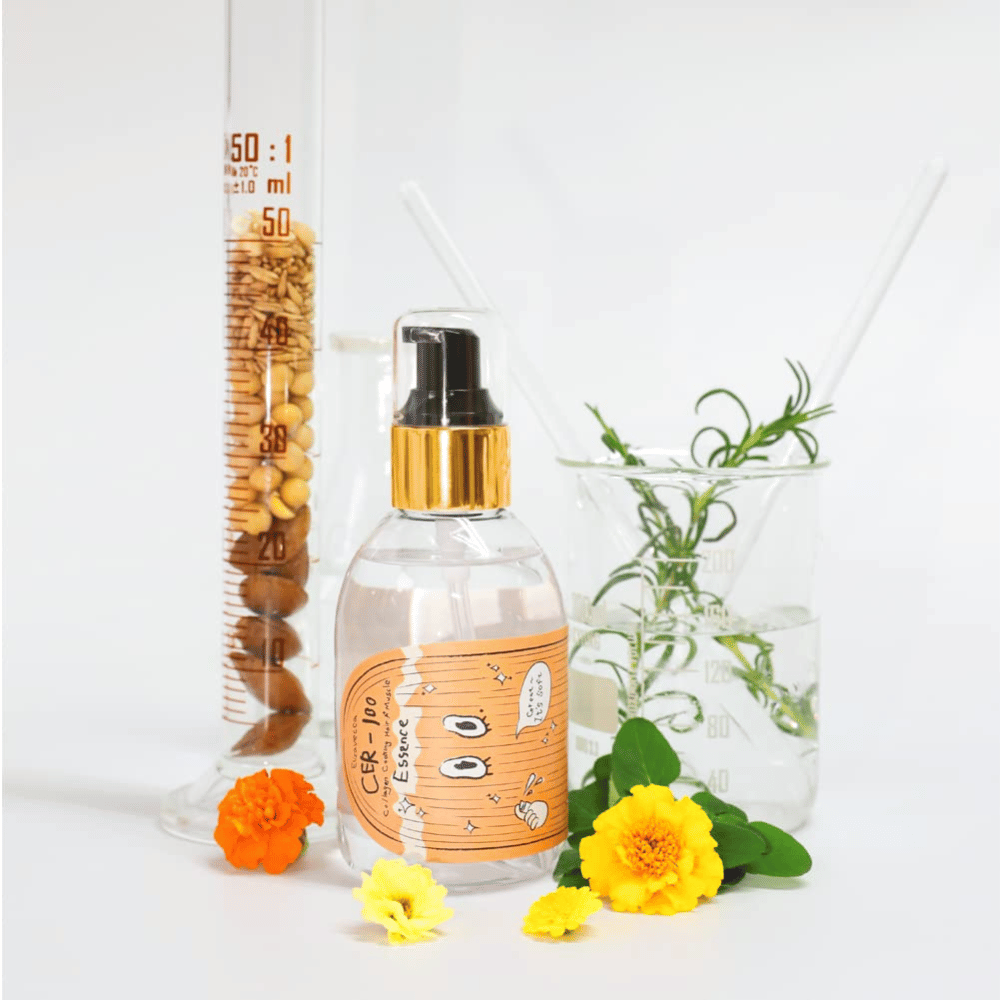 CER-100 Hair Essence junto con flores y cristalería de laboratorio que resaltan los ingredientes y el cuidado del cabello.