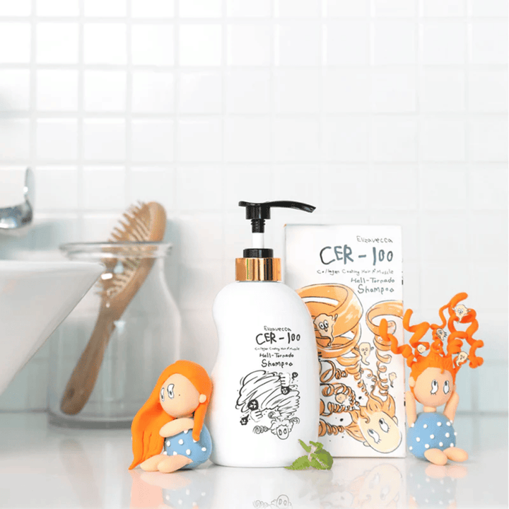 Elizavecca CER-100 Shampoo y la caja se muestran en un entorno de baño junto a un cepillo para el cabello y figuras decorativas. La imagen transmite una rutina cotidiana de cuidado capilar y el uso del producto en un entorno doméstico.