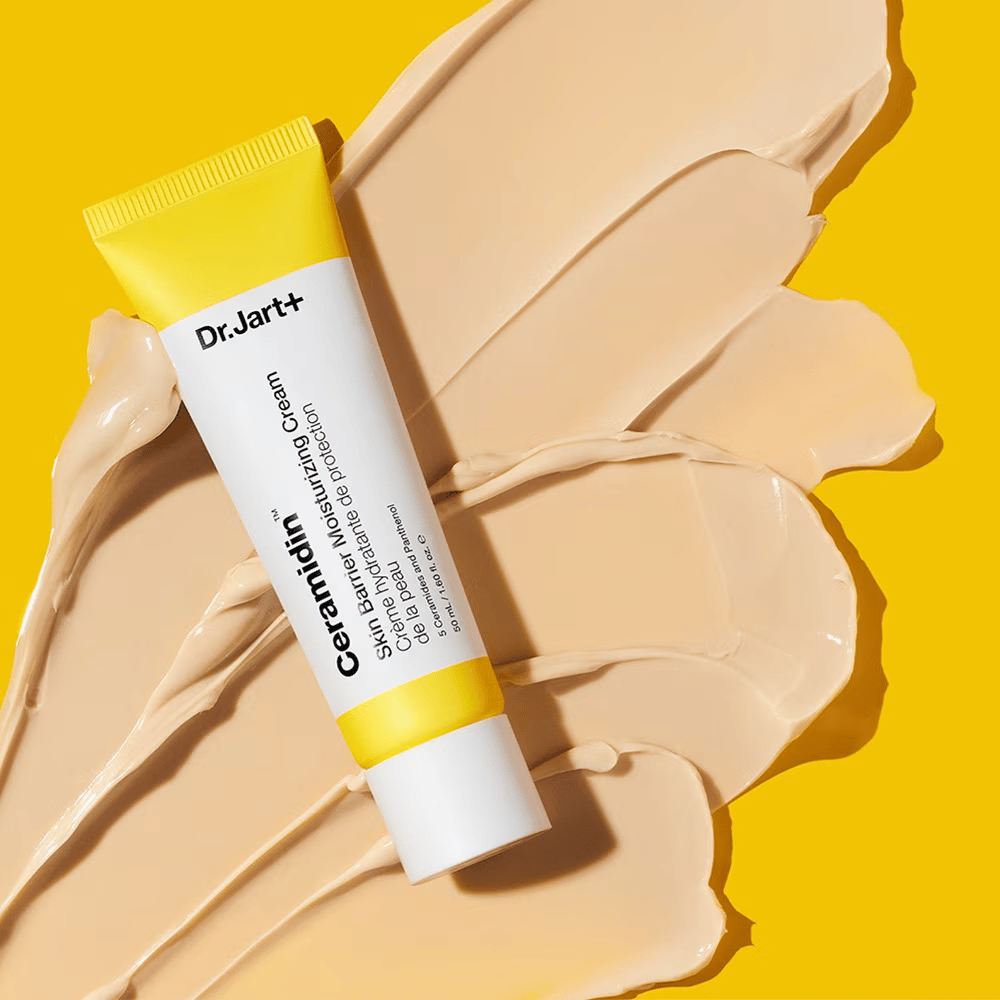 Tubo con Dr. Jart+ Ceramidin Skin Barrier Moisturizing Cream sobre un fondo amarillo con crema esparcida.