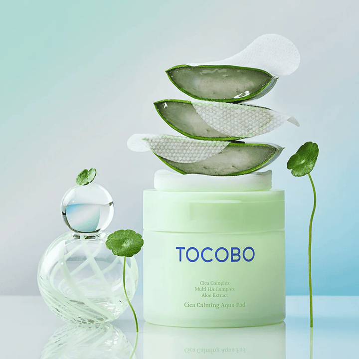 TOCOBO Cica Calming Aqua Pad se muestra junto con almohadillas de tónico, aloe vera y centella asiática. La imagen destaca los ingredientes hidratantes y calmantes del producto.