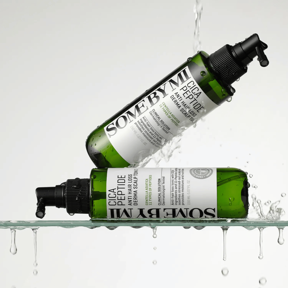 Dos botellas SOME BY MI Cica Peptide Anti Hair Loss Derma Scalp Tonic están en y sobre el agua con gotas salpicando, botellas verdes con boquilla de spray negra y etiqueta blanca.