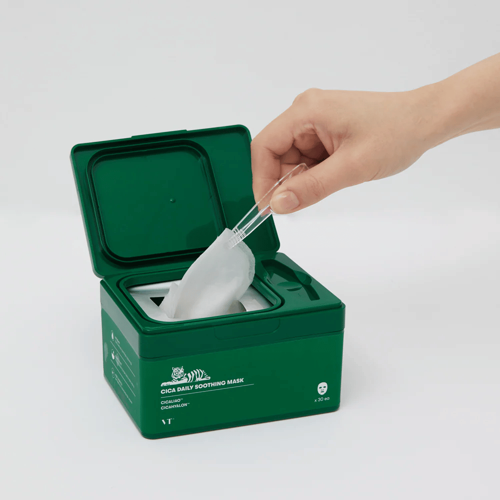 Mano usa una pinza para sacar una Sheet mask de un contenedor verde marcado "Cica Daily Soothing Mask".