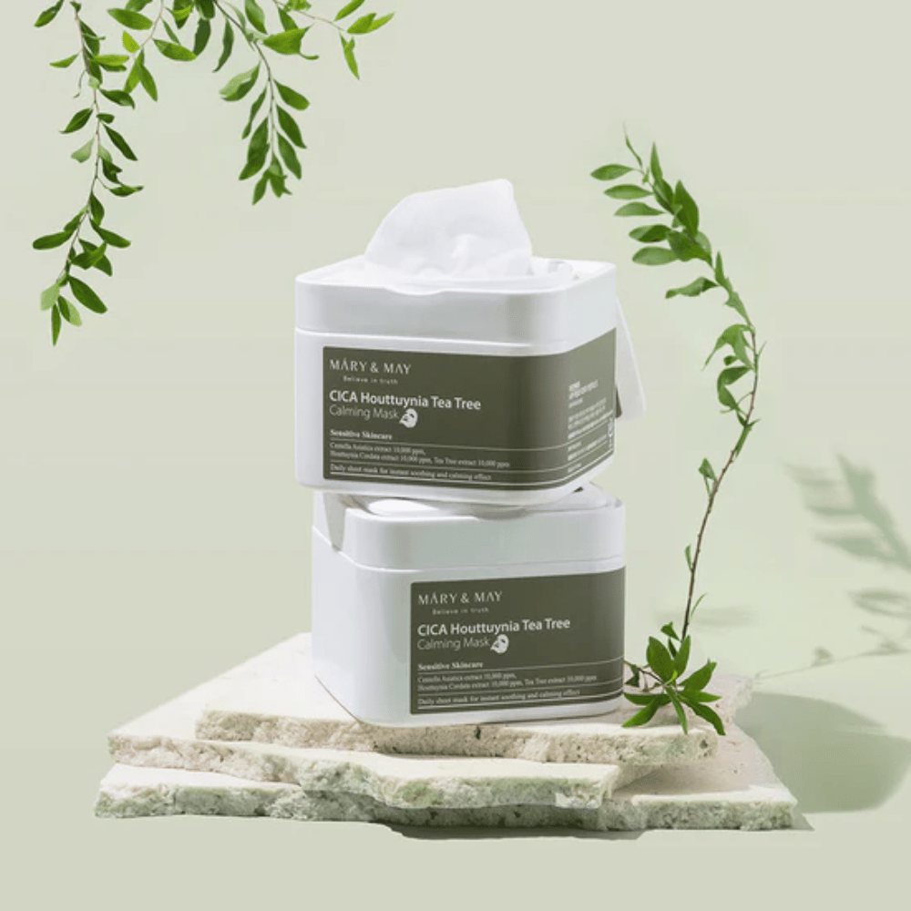 Dos tarros de Mary & May Cica Houttuynia Tea Tree Calming Mask colocados sobre piedra natural con detalles de plantas verdes – mascarillas calmantes para piel sensible.