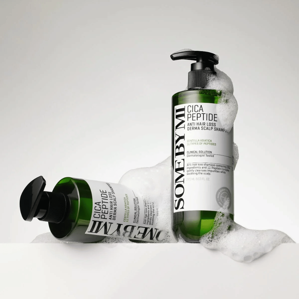 Dos botellas de SOME BY MI Cica Peptide Anti Hair Loss Derma Scalp Shampoo cubiertas de espuma, de pie y acostadas sobre un fondo blanco.