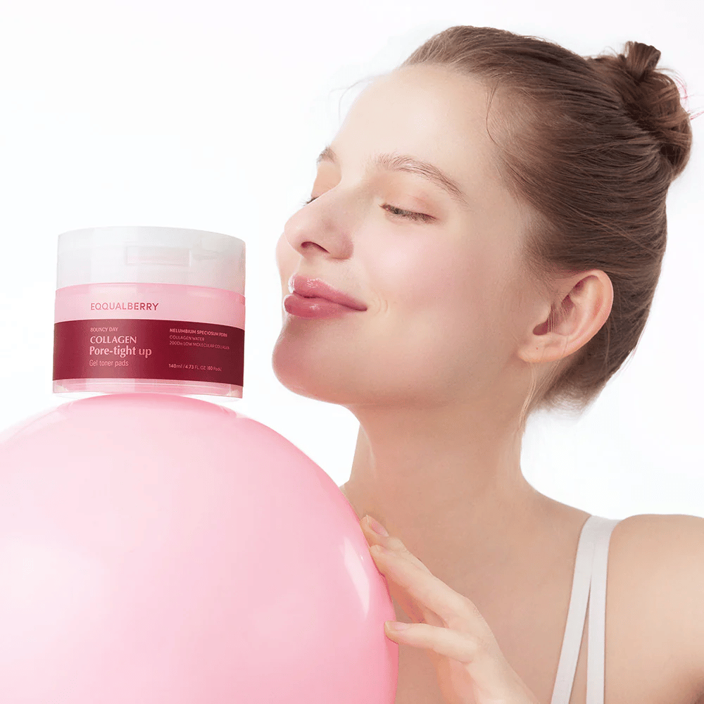 Una mujer está de pie con una bola rosa y un frasco Collagen Pore-Tight Up Gel Toner Pads, mientras sonríe y sostiene el frasco cerca de su cara. El frasco está etiquetado con el nombre del producto y contiene almohadillas tonificantes que ayudan a reafirmar la piel y reducir el tamaño de los poros.