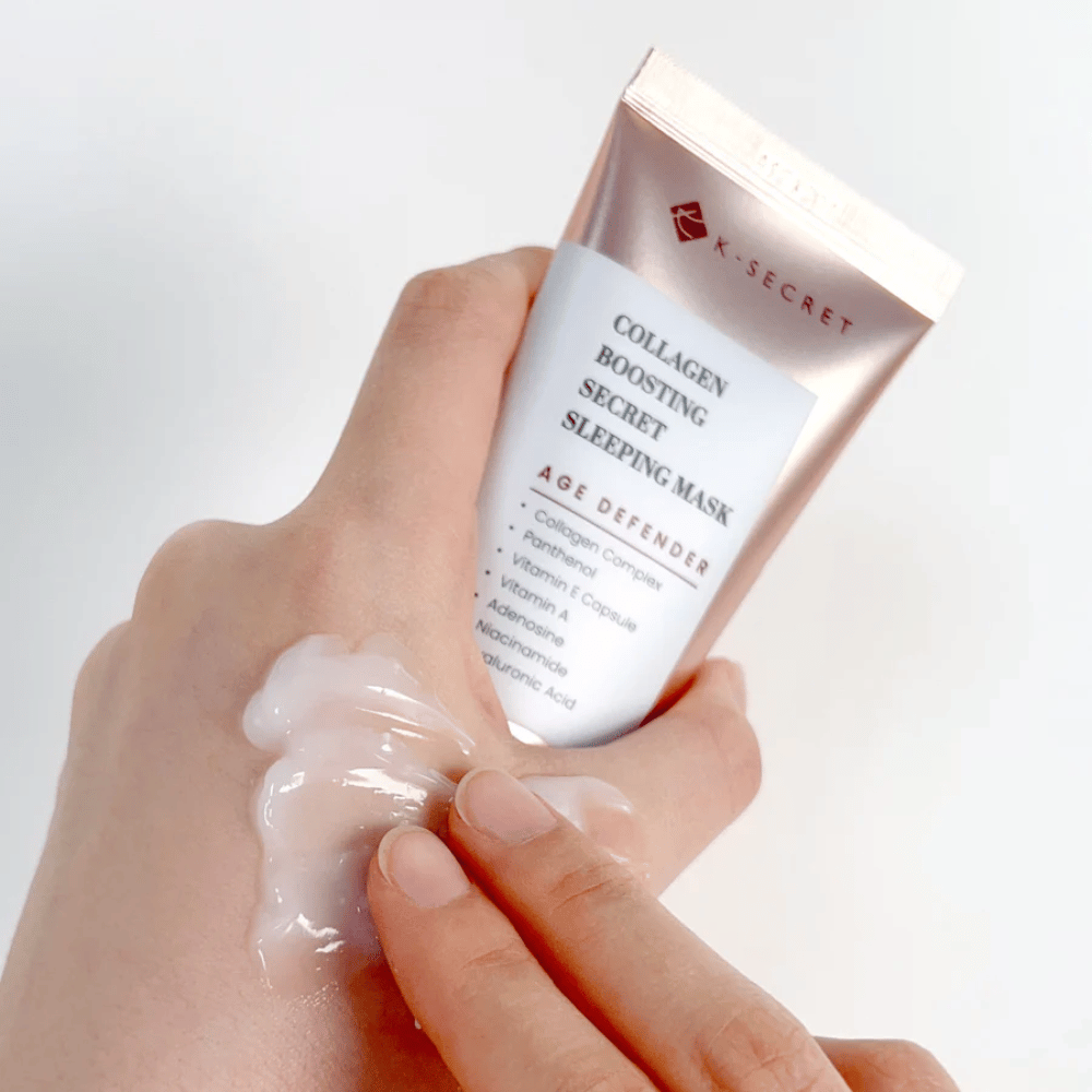 Una mano sostiene Collagen Boosting Secret Sleeping Mask mientras la otra aplica una cantidad generosa de crema en la parte superior de la mano, mostrando la consistencia y aplicación del producto.