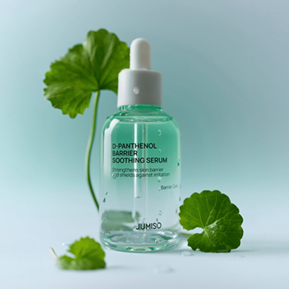 Jumiso D-Panthenol Barrier Soothing Serum en botella de vidrio transparente con pipeta, colocada con hojas verdes en el fondo.