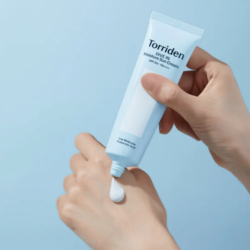 Torriden DIVE-IN Moisture Sun Cream SPF50+ PA++++ aplicado en la mano para mostrar la textura ligera y cremosa de la crema solar hidratante.