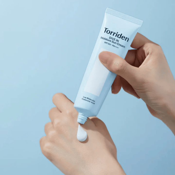 Torriden DIVE-IN Moisture Sun Cream SPF50+ PA++++ aplicado en la mano para mostrar la textura ligera y cremosa de la crema solar hidratante.