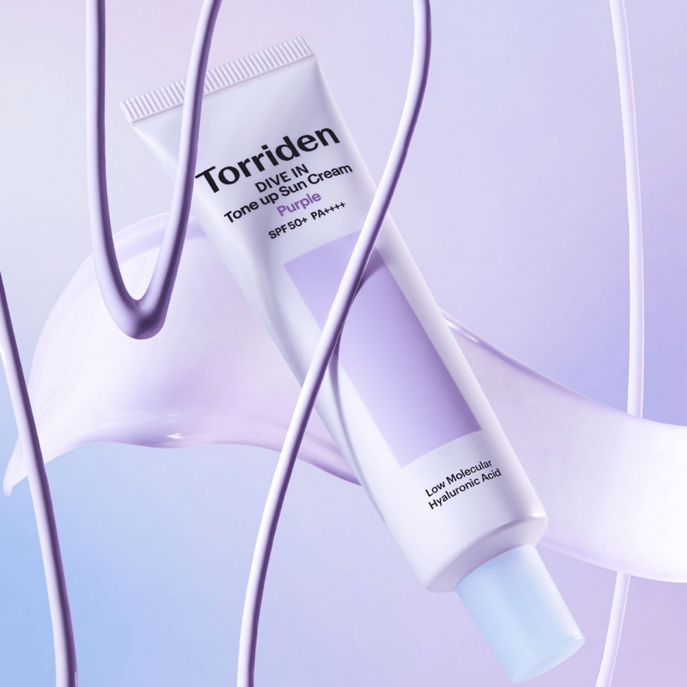 Torriden DIVE IN Tone Up Sun Cream Purple SPF50+ PA++++ presentada en un entorno creativo de producto con detalles lilas que resaltan la fórmula hidratante.