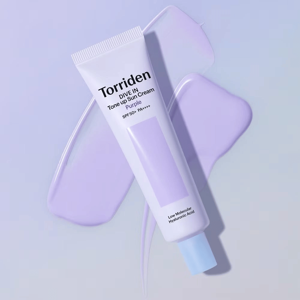 Torriden DIVE IN Tone Up Sun Cream Purple colocada sobre crema lila extendida que destaca el efecto unificador del tono y aportador de luminosidad.