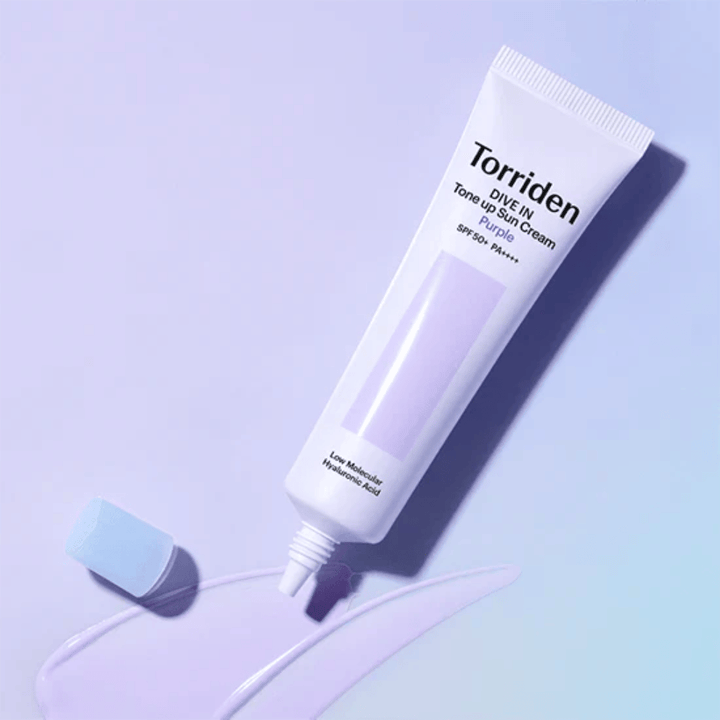 Tubo abierto de Torriden DIVE IN Tone Up Sun Cream Purple con textura de protector solar con tono lila que muestra la fórmula correctora del color del producto.