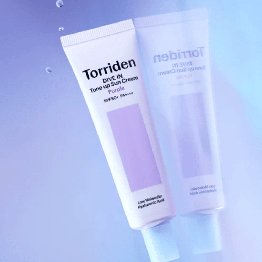 Torriden DIVE IN Tone Up Sun Cream Purple SPF50+ PA++++ fotografiada sobre un suave fondo lila que resalta el diseño reflectante de la luz del producto.