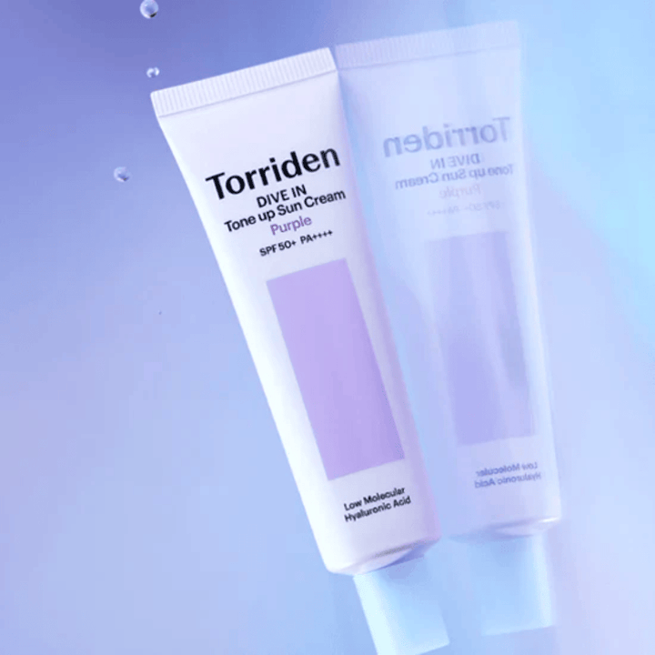 Torriden DIVE IN Tone Up Sun Cream Purple SPF50+ PA++++ fotografiada sobre un suave fondo lila que resalta el diseño reflectante de la luz del producto.