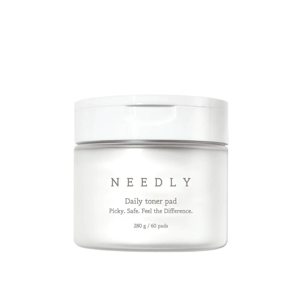 Un frasco blanco con Needly Daily Toner Pad. El empaque tiene un texto minimalista que describe el producto y contiene 280 g, equivalentes a 60 almohadillas de tónico. El texto dice 'Picky. Safe. Feel the Difference.