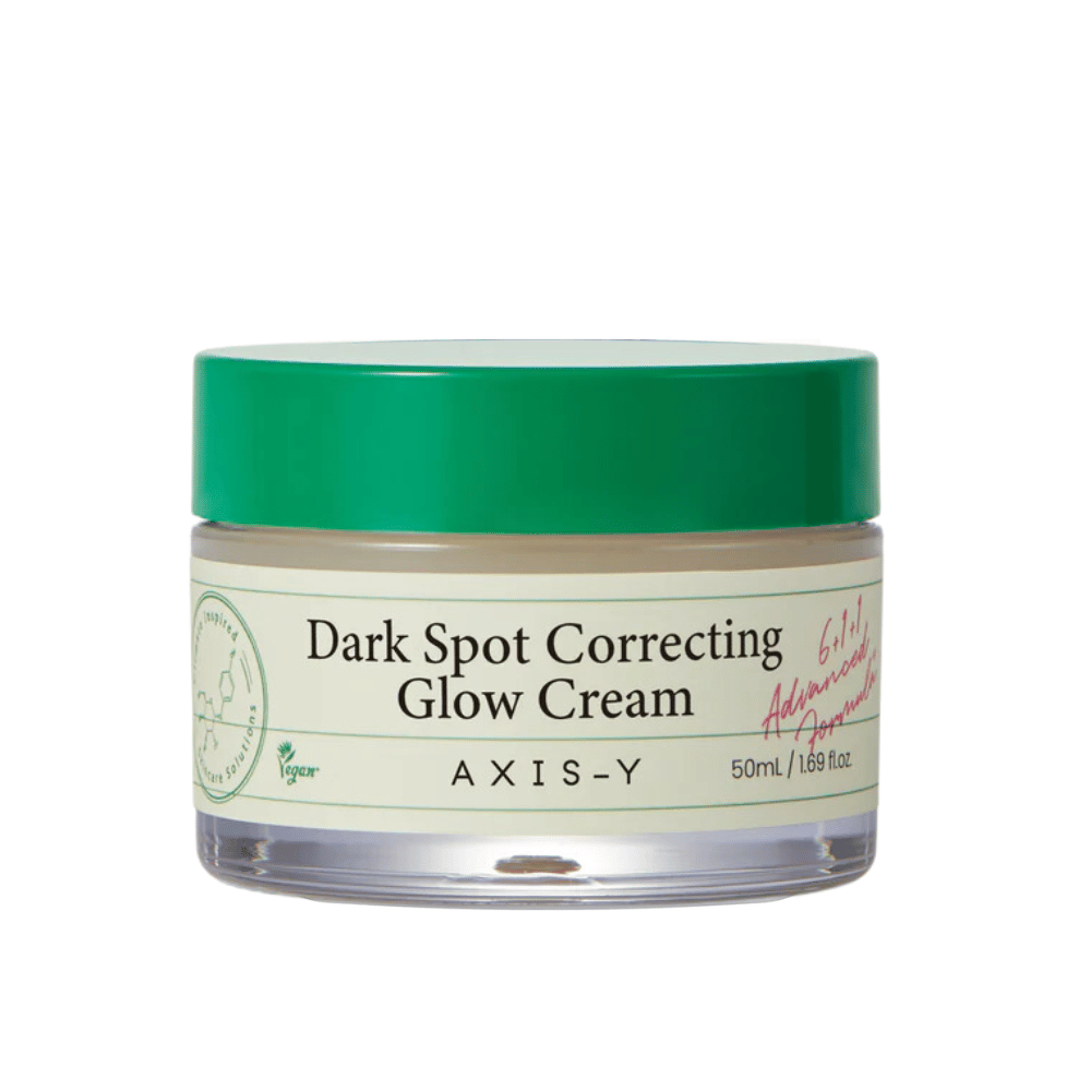 Un tarro de "AXIS-Y Dark Spot Correcting Glow Cream". Esta crema está diseñada para corregir manchas oscuras y dar brillo a la piel. El empaque es elegante con una base transparente y una tapa verde llamativa.