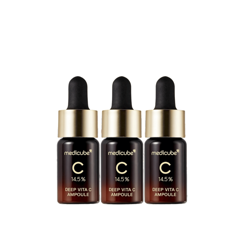 Tres botellas de Medicube Deep Vita C Ampoule, con 14,5 % de vitamina C, dispuestas en línea. Las botellas tienen un diseño elegante con base marrón oscuro y tapón dorado. Perfecto para un tono de piel más claro y una textura de piel más uniforme.
