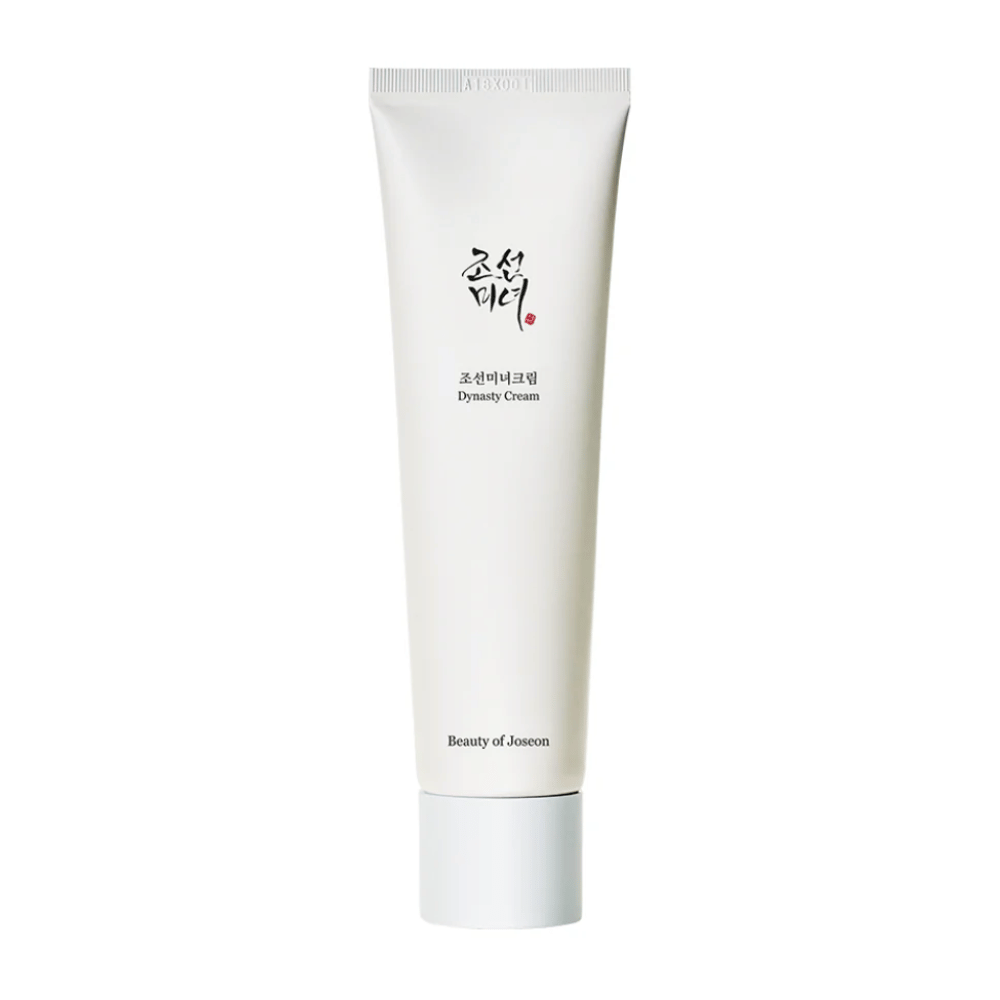La imagen muestra un tubo de "Beauty of Joseon Dynasty Cream". El esbelto tubo blanco tiene elementos de diseño minimalista, incluyendo texto elegante en negro y rojo. Este producto para el cuidado de la piel promete nutrir y vitalizar la piel, reflejando los secretos de belleza históricos de la dinastía Joseon.