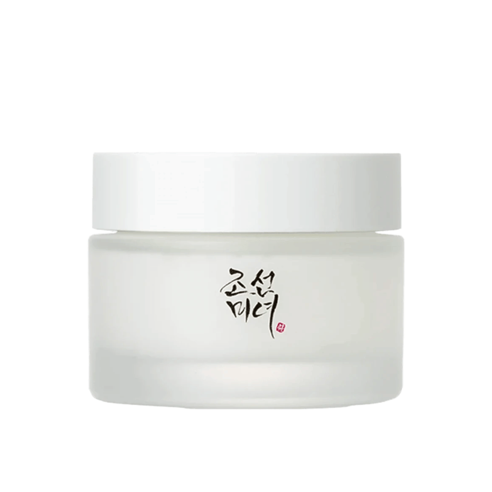 La imagen muestra un frasco "Beauty of Joseon Dynasty Cream". El envase es de vidrio esmerilado con una simple tapa blanca, elegantemente decorada con caligrafía coreana tradicional en negro. El producto está diseñado para ofrecer cuidado de la piel nutritivo inspirado en antiguas rutinas de belleza coreanas.